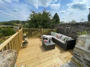 a wooden deck with a couch and a table at The Barn Cottage in Oakworth