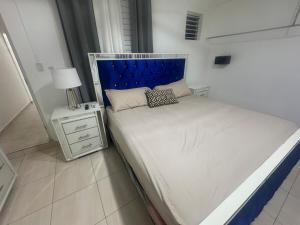 a white bed with a blue headboard in a bedroom at Apto Próximo al Aeropuerto Gregorio Luperón in Puerto Plata