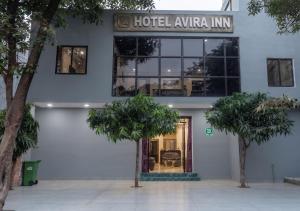 a hotel entrance with two trees in front of a building at Hotel Avira Inn-Opp Lucknow HighCourt in Lucknow