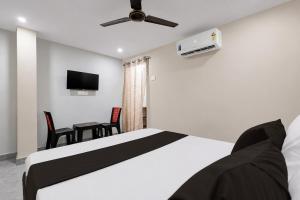a bedroom with a bed with a ceiling fan and a table at Hotel O Saikrishna Inn in Rājahmundry