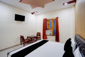 a bedroom with a bed and a table and a window at Hotel O Jhandi Palace in Lakhīmpur