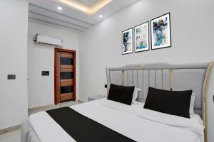 a bedroom with a large white bed with black pillows at Hotel O Bay Inn in New Delhi