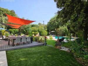a patio with an orange umbrella over a lawn at Villa piscine jacuzzi Mas la Bregeonière in Roquefort-les-Pins +5 photos