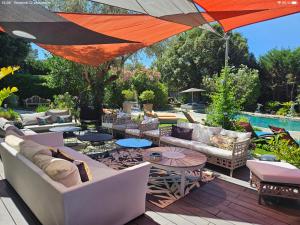 a patio with couches and tables and a pool at Villa piscine jacuzzi Mas la Bregeonière in Roquefort-les-Pins