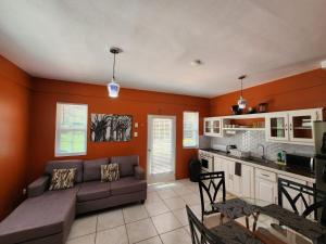 a living room with a couch and a kitchen at Coral Apt Tropical Apartments Tobago in Scarborough