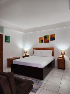 a bedroom with a bed and two lamps and a couch at Coral Apt Tropical Apartments Tobago in Scarborough +21 photos