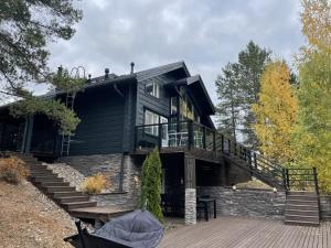 a black house with a deck and stairs at Villa Loiste Himos Chalet with Hot Tub in Jämsä