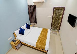 a bedroom with a bed with blue pillows and a television at Hotel Avira Inn-Opp Lucknow HighCourt in Lucknow +9 photos