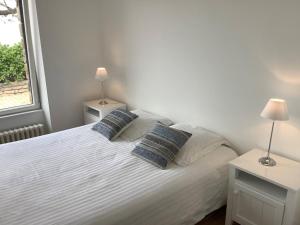 a bedroom with a white bed with two pillows at Paradis sur l'Aber in Landéda