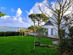 a house with a swing in a yard next to the water at Paradis sur l'Aber in Landéda