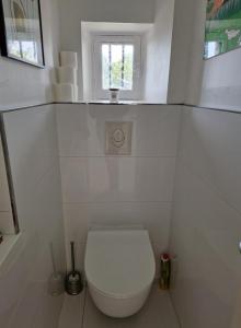a white bathroom with a toilet and a window at Paradis sur l'Aber in Landéda