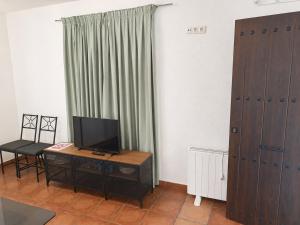 a living room with a television and a table with a chair at Apartamentos Las Fuentes in Labajos