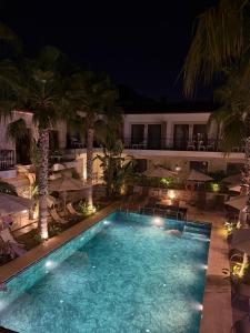 a swimming pool with chairs and umbrellas at night at İcarus Alaçatı in Çeşme