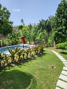 a garden with a swimming pool and plants at Coral Apt Tropical Apartments Tobago in Scarborough