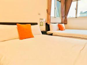 two beds with orange and white pillows in a room at Ferry Bow in Jincheng