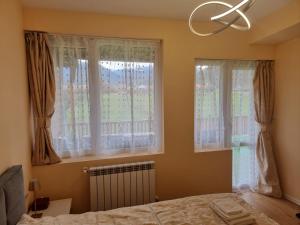 a bedroom with a bed and two windows at Villa Nikol Apartment #4 in Raduil