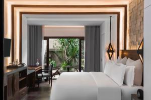 a bedroom with a large white bed and a desk at Jaya House River Park in Siem Reap