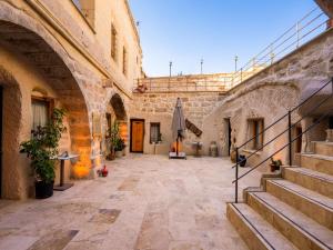 an empty courtyard of a building with stairs and an umbrella at Memories Cave House in Uçhisar