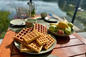 a table topped with waffles and a bowl of fruit at Szept Wody Kaszuby in Lubiana