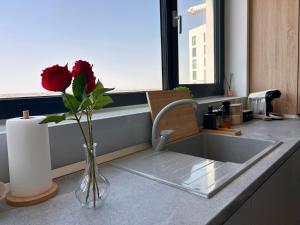 a kitchen sink with a vase with a rose in it at V'One - Cozy & Quiet Apartment - Free Parking in Timişoara +6 photos