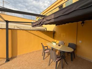 a table and chairs on a balcony with a yellow wall at La Vista Suite and Rooms in Ladispoli
