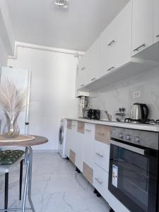 a white kitchen with a stove and a table at Bella Home Residence in Roşu