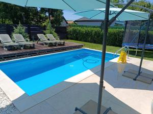 a swimming pool with an umbrella next to chairs and an umbrella at MARINA HOUSE pool & garden in Beograd