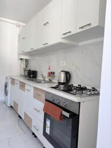 a kitchen with white cabinets and a stove top oven at Bella Home Residence in Roşu +6 photos