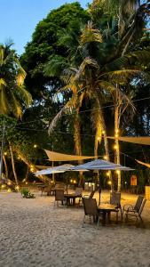 a beach with tables and chairs and palm trees at night at Almonds & Corals Boutique Hotel in Puerto Viejo
