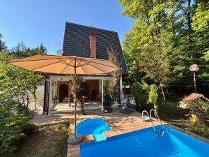 a pool with an umbrella next to a house at Forest Oasis Slatina in Slatina Varoš