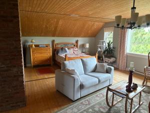 a bedroom with a bed and a couch and a chair at La Maison Pamaljolie in Ayers Cliff