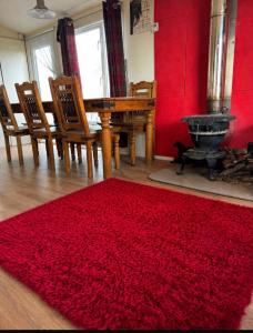 a red rug in a room with a table and a fireplace at The barn in Carmarthen