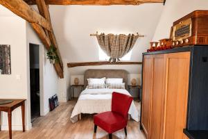 a bedroom with a bed and a red chair at Le Grenier - Air conditioning - Free parking in Nogent-sur-Vernisson +2 photos
