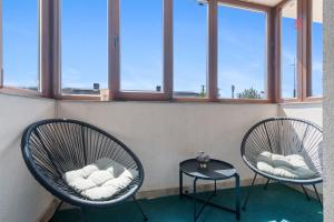 two chairs and a table in a room with windows at Crina Studio in Bragadiru
