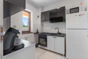 a white kitchen with a refrigerator and a sink at Crina Studio in Bragadiru +4 photos