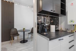 a kitchen with white cabinets and a table and chairs at Crina Studio in Bragadiru