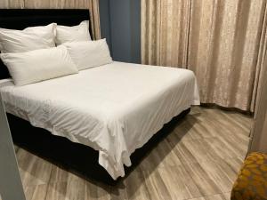 a bedroom with a bed with white sheets and pillows at Zahara Lodge in Victoria Falls