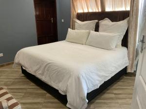 a large bed with white sheets and pillows at Zahara Lodge in Victoria Falls