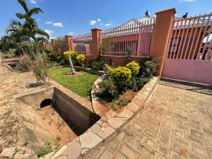 a garden in front of a building with a fence at Zahara Lodge in Victoria Falls