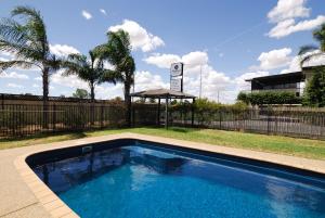 einen Pool in einem Garten mit einem Zaun und Bäumen in der Unterkunft Mayfair Motel in West Wyalong