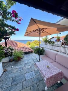 a patio with a table and an umbrella at Endless Blue Maisonette in Agios Ioannis Pelio