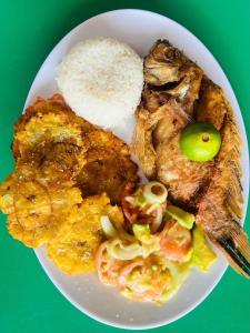 a plate of food with meat and rice on a green table at Vista Linda Cabaña in Playa Blanca