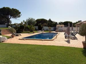 a swimming pool in a yard with chairs and umbrellas at Luxury Villa near Vila Sol Golf Resort - Pool & Garden in Quarteira