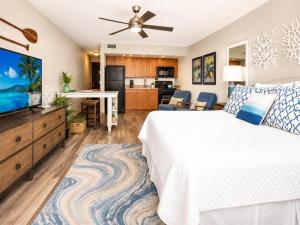 a bedroom with a white bed and a flat screen tv at Royal Kahana 318 Studio Condo in Kahana