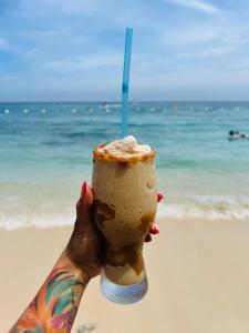 a person holding up a drink in front of the beach at Vista Linda Cabaña in Playa Blanca