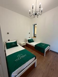 a bedroom with two beds with green sheets and a chandelier at Calm Barnhouse Lankaran in Lankaran