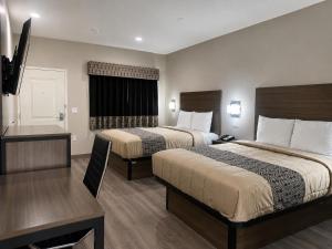 a hotel room with two beds and a television at Hotel Royale - Houston Hobby Airport in Houston