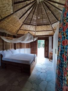 a bedroom with a bed in a straw roof at REFUGE du MONT AGOU in Liatonou +56 photos