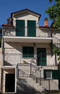an apartment building with stairs and green shutters at Kuća za odmor Mate 