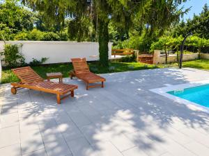 two wooden benches sitting next to a swimming pool at Hiža Bili in Svetvinčenat